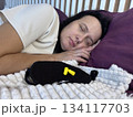 Sleeping adult woman with sleep mask and earplugs beside her, concept of peaceful rest and noise protection 134117703
