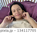 Close up of adult brunette woman inserting yellow earplugs, noise protection for healthy sleep, deep rest, insomnia prevention and peaceful home bedroom atmosphere 134117705