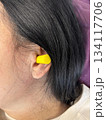 Close up of adult brunette woman inserting yellow earplugs, noise protection for healthy sleep, deep rest, insomnia prevention and peaceful home bedroom atmosphere 134117706