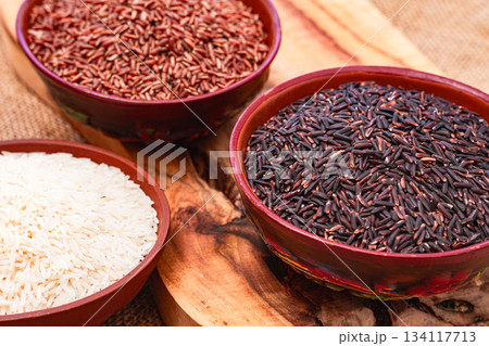set of red and black and white rice, in a bowl, on a wooden surface, rustic style, top view 134117713