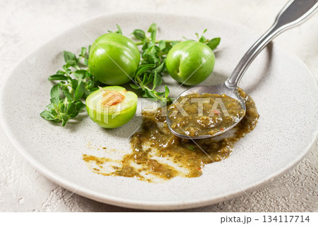 a spoon with tkemali sauce, on a plate, with cherry plum and mint, top view, no people, 134117714