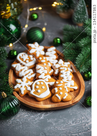 Homemade Decorated Gingerbread Cookies with Icing on Wooden Plate and Pine Decor Homemade Decorated Gingerbread Cookies with Icing on Wooden Plate and Pine Decor 134117863