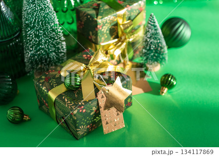 Christmas Gifts with Mini Trees and Green-Gold Ornaments on Festive Background Christmas Gifts with Mini Trees and Green-Gold Ornaments on Festive Background 134117869