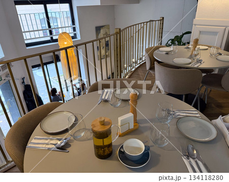 Cozy cafe interior with served tables and warm light. Hospitality, social comfort, dining culture and aesthetic food ambience. 134118280