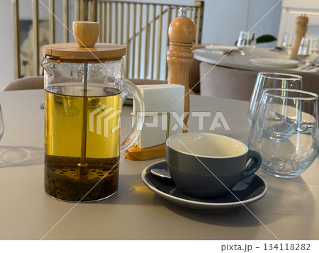 Tea pot with brewing herbs on cafe table. Warm atmosphere, slow living, comfort, lunch break mood. Tea pot with brewing herbs on cafe table. Warm atmosphere, slow living, comfort, lunch break mood. 134118282