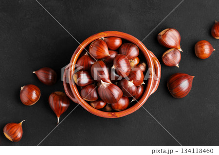 Fresh chestnuts in a clay bowl on black background 134118460