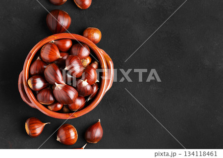 Fresh chestnuts in a clay bowl on black background 134118461