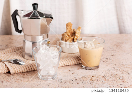 Iced coffee, espresso cups and moka pot on textured beige stone table 134118489
