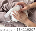 Close up of a portable electric nebulizer inhaler held in the hands of a sick adult woman at home, modern medical device for respiratory therapy, asthma and cold treatment equipment, healthcare 134119207