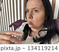 Adult woman using a home nebulizer inhaler while sitting in a cozy bedroom, respiratory treatment at home for breathing relief, healthcare and medical therapy concept, realistic lifestyle scene 134119214