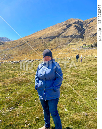A woman is standing in a field wearing a blue jacket and a black hat A woman is standing in a field wearing a blue jacket and a black hat 134120265