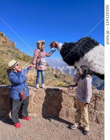 A woman is holding a stuffed animal while two children look on A woman is holding a stuffed animal while two children look on 134120300