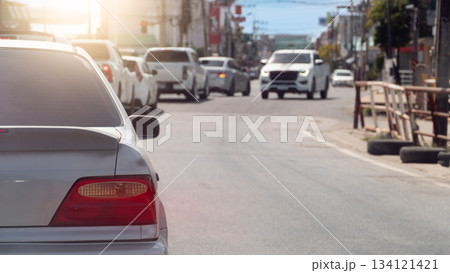 Rear side view of car in the traffic jam at day time. Many car drive behind the queue arranged in a curved line. With blurred of other car driving on the opposite lens on asphalt road at day. Rear side view of car in the traffic jam at day time. Many car drive behind the queue arranged in a curved line. With blurred of other car driving on the opposite lens on asphalt road at day. 134121421