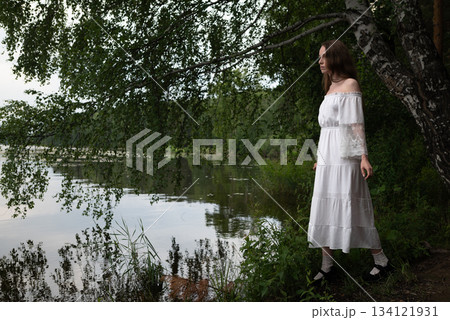 Elegance by the Lake: Woman in White Off-Shoulder Dress Among Birch Trees 134121931