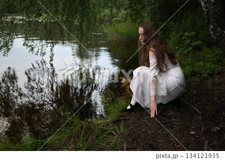 Contemplation by the Water: Woman in White Dress Gazing at the Lake 134121935