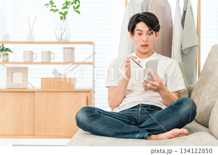 リビングのソファーに座り読書する若いアジア人男性 リビングのソファーに座り読書する若いアジア人男性 134122850