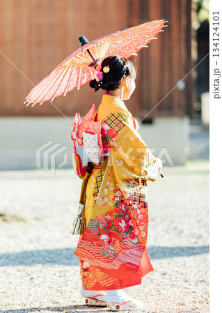七五三で和傘をさして神社にお参りをする女の子 134124101