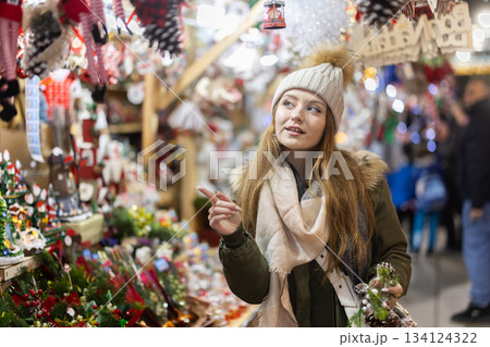 Young woman looking at decorated shop windows in the market Young woman looking at decorated shop windows in the market 134124322