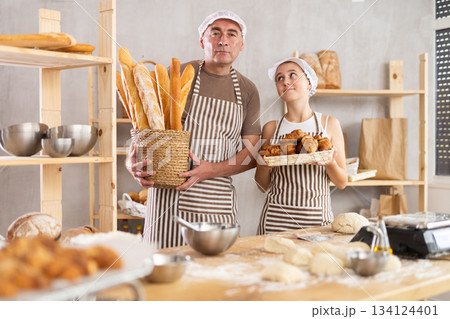 Girl and man bakers with basket of baguettes and croissants 134124401