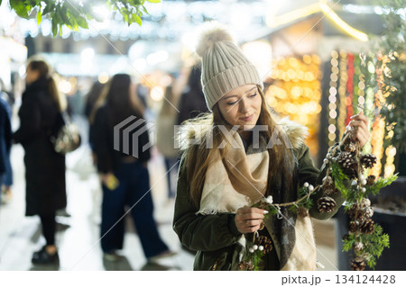Girl looks at garland made of fir cones and brunchs, Xmas atmosphere 134124428