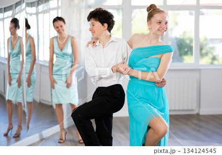 Girl and boy in evening dresses learn to dance the foxtrot in choreographic studio Girl and boy in evening dresses learn to dance the foxtrot in choreographic studio 134124545