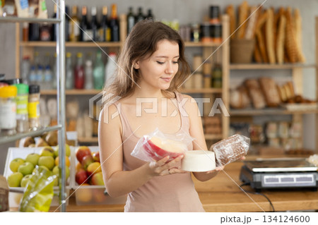 Young female customer choosing packaged cheese in grocery store 134124600