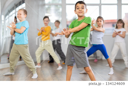 Children studying modern style dances with female teacher in dance class Children studying modern style dances with female teacher in dance class 134124609