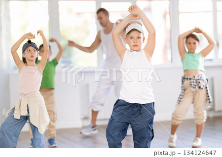 Young happy boy and group of positive children practicing energetic hip hop movements at dance school 134124647