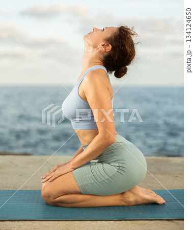 Yoga practice on embankment, female athlete fulfil carry out padmasana svastikasana, Siddhasana 134124650