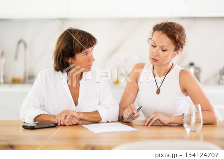 Two woman at table and trying to figure out finance problem and thinking about bills at home 134124707