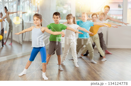 Children do warm-up exercises in studio, prepare for pair dance class 134124778