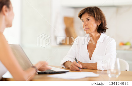 Woman listen attentively and intently to woman of seller, who tells about advantages of making microloan in credit institution 134124952