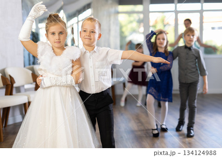 Little children in elegant dresses practicing waltz dance in school hall Little children in elegant dresses practicing waltz dance in school hall 134124988