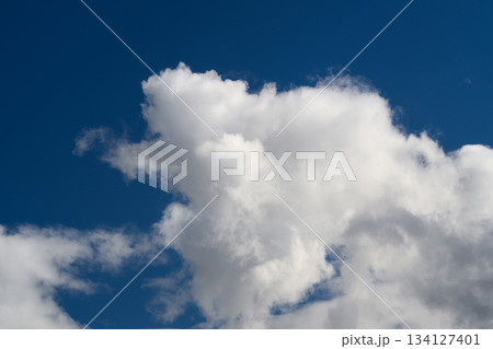 Fluffy white clouds drifting gracefully against a brilliant bright blue sky in the background Fluffy white clouds drifting gracefully against a brilliant bright blue sky in the background 134127401