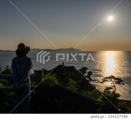 夕暮れの岬と女性 134127590