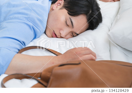 ベッドを寝落ちして朝を迎える若い男性 134128429