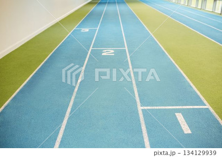 Blue track lanes are extending into perspective in flat design with green turf, white wall, windows 134129939