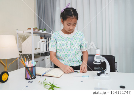Child looking through microscope on white background. Kid scientist learning biology. Child looking through microscope on white background. Kid scientist learning biology. 134131747