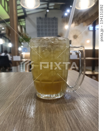 Iced lemon tea glass mug ice cubes cold drink cafe table wooden surface refreshing vibe Iced lemon tea glass mug ice cubes cold drink cafe table wooden surface refreshing vibe 134131892
