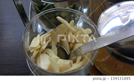 Sliced garlic metal spoon glass bowl chili green pepper condiment station kitchen raw fresh spicy aroma cooking ingredient 134131895