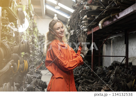 Female technician worker working in garage scrap yard old car part workshop warehouse. Female technician worker working in garage scrap yard old car part workshop warehouse. 134132538