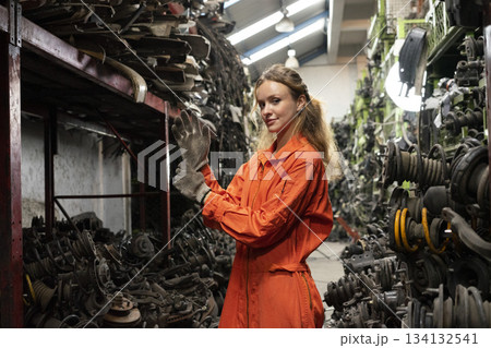 Female technician worker working in garage scrap yard old car part workshop warehouse. Female technician worker working in garage scrap yard old car part workshop warehouse. 134132541