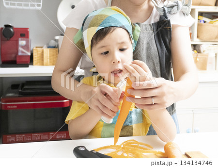 キッチンで親子で人参の皮を剥く母親と息子 キッチンで親子で人参の皮を剥く母親と息子 134134746
