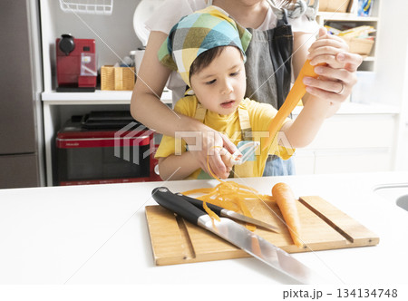 キッチンで親子で人参の皮を剥く母親と息子 134134748