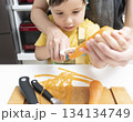 キッチンで親子で人参の皮を剥く母親と息子 134134749