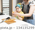 キッチンで親子で人参の皮を剥く母親と息子 134135299