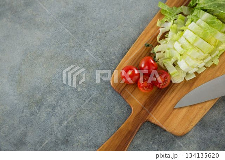 Chopped lettuce with tomato on cutting board 134135620