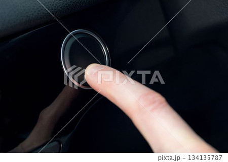 Finger pressing a button in a car Finger pressing a button in a car 134135787