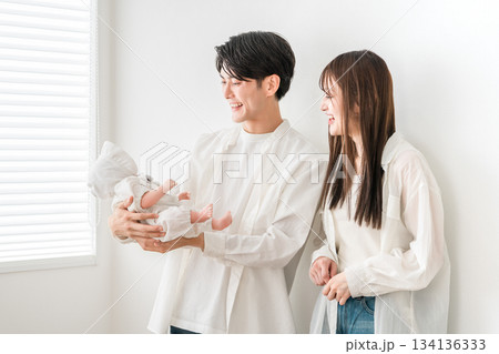 リビング・ダイニングで赤ん坊・赤ちゃんをあやす若い夫婦 リビング・ダイニングで赤ん坊・赤ちゃんをあやす若い夫婦 134136333