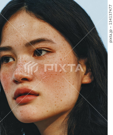 Portrait of a young woman with freckles against a clear sky during daytime 134137477